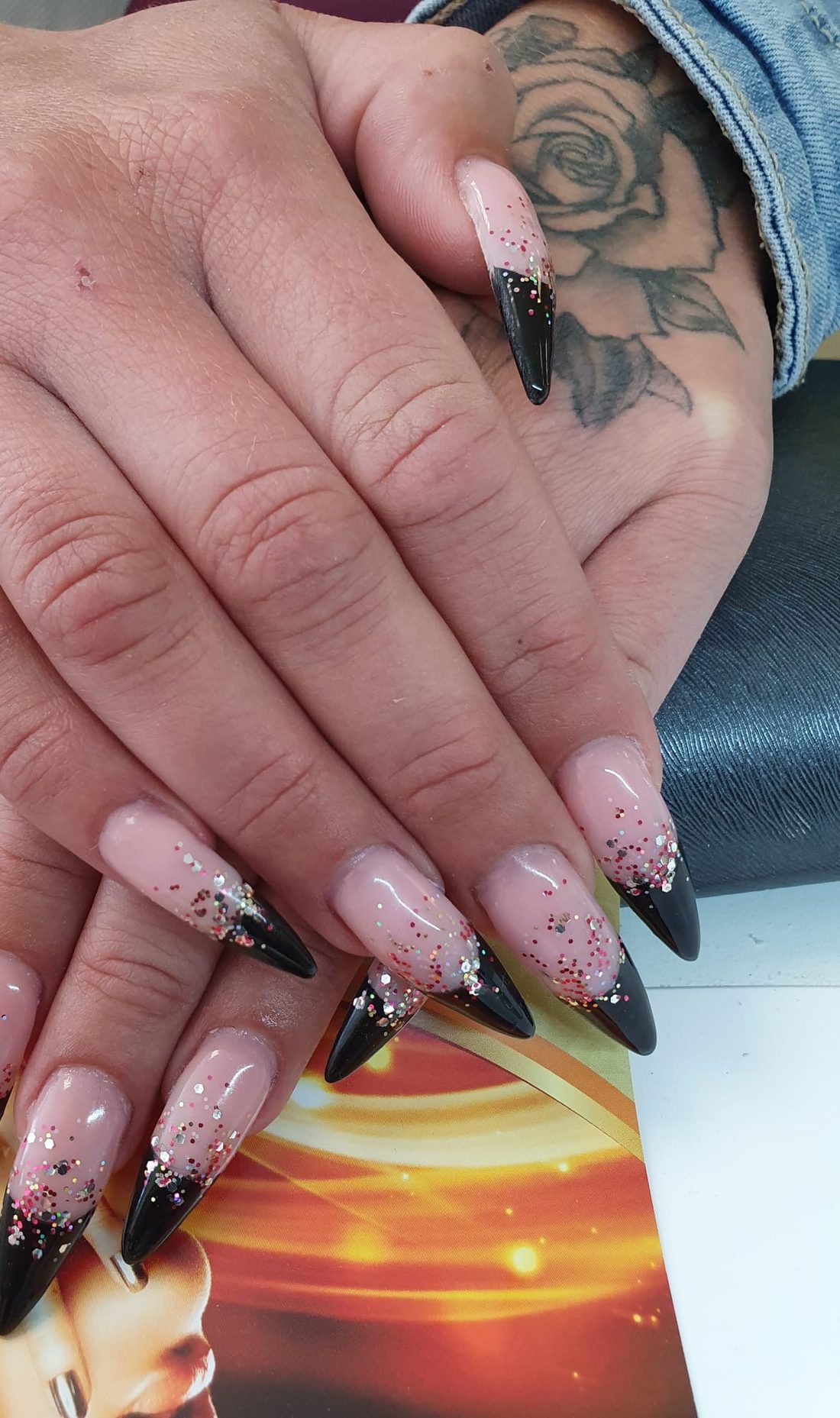 Stiletto-Nägel mit schwarzer Glitzerspitze über nudefarbener Basis