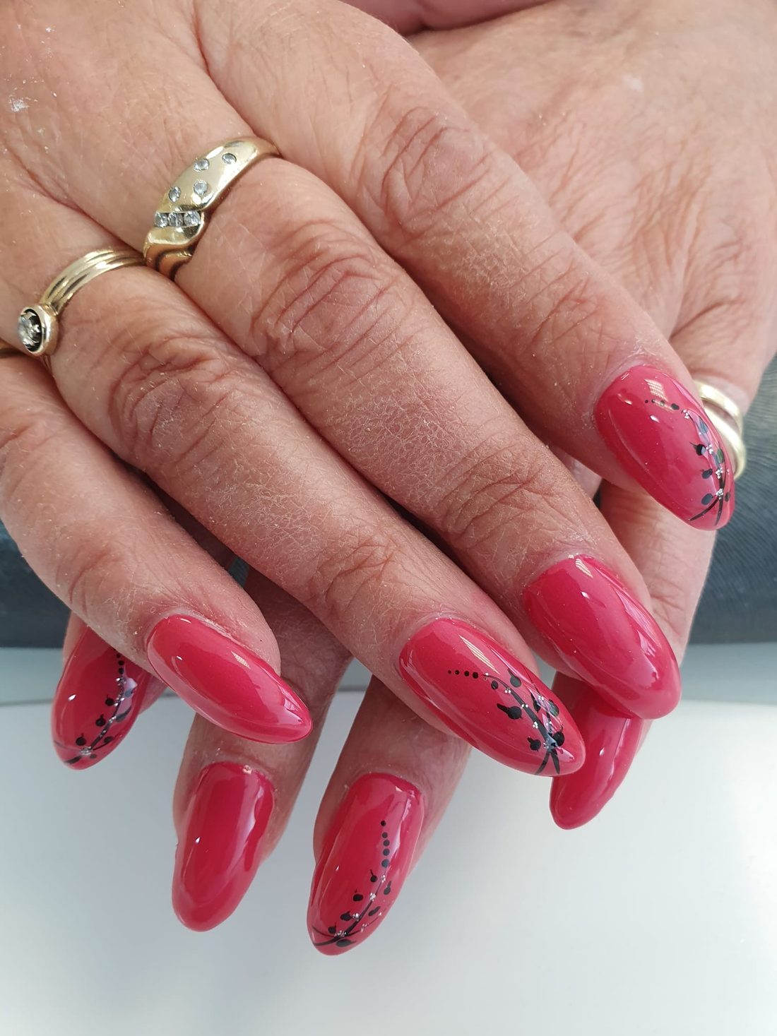 Magentafarbene Mandel-Nägel mit zartem schwarzem Blumen-Nailart und Silberpunkten