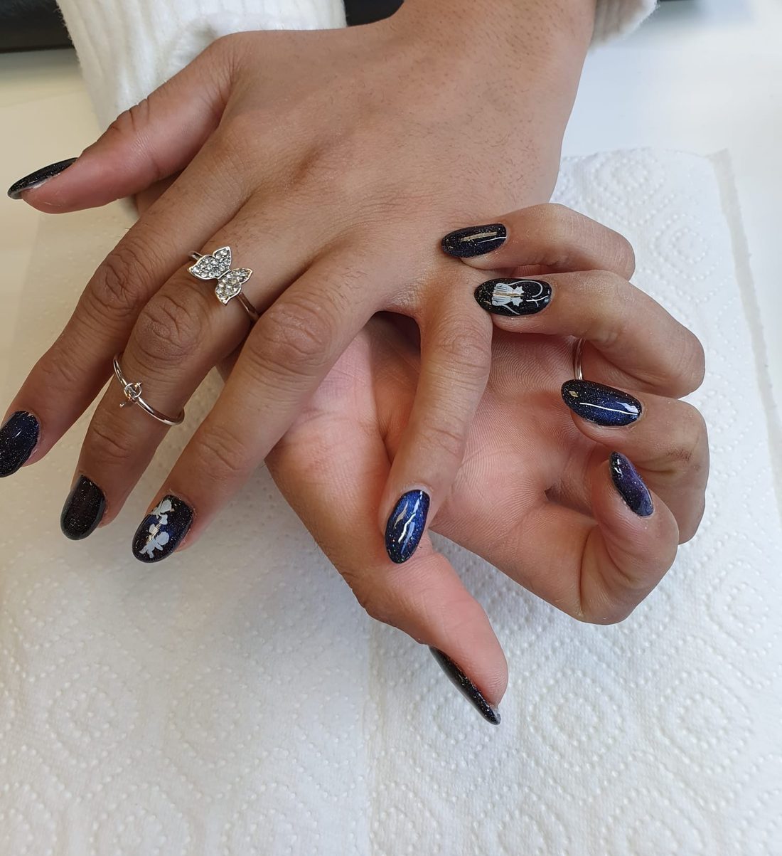 Marineblaue Gel-Nägel mit Galaxie-Glitzer und weißen Nail-Art-Akzenten in Mandelform