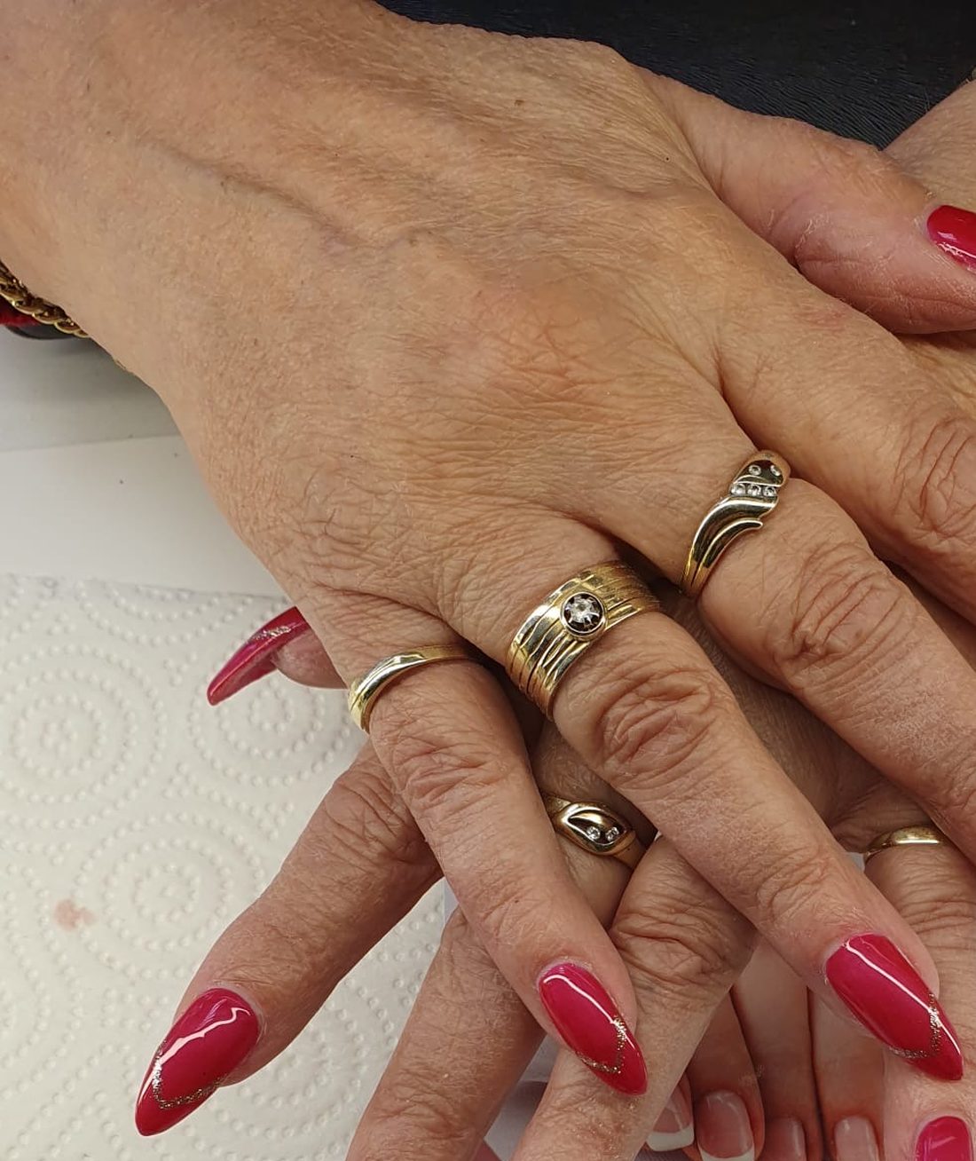 Rote glänzende Gel-Nägel mit feinen goldenen Akzentlinien