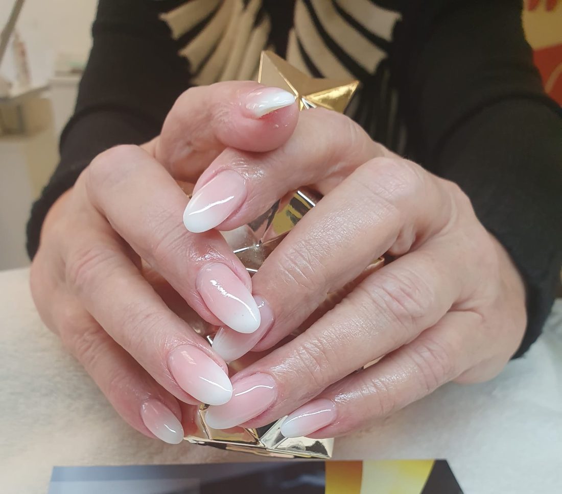 Weiß-rosa Ombre-Nägel in Mandelform, abgelegt auf einem goldenen Deko-Stern